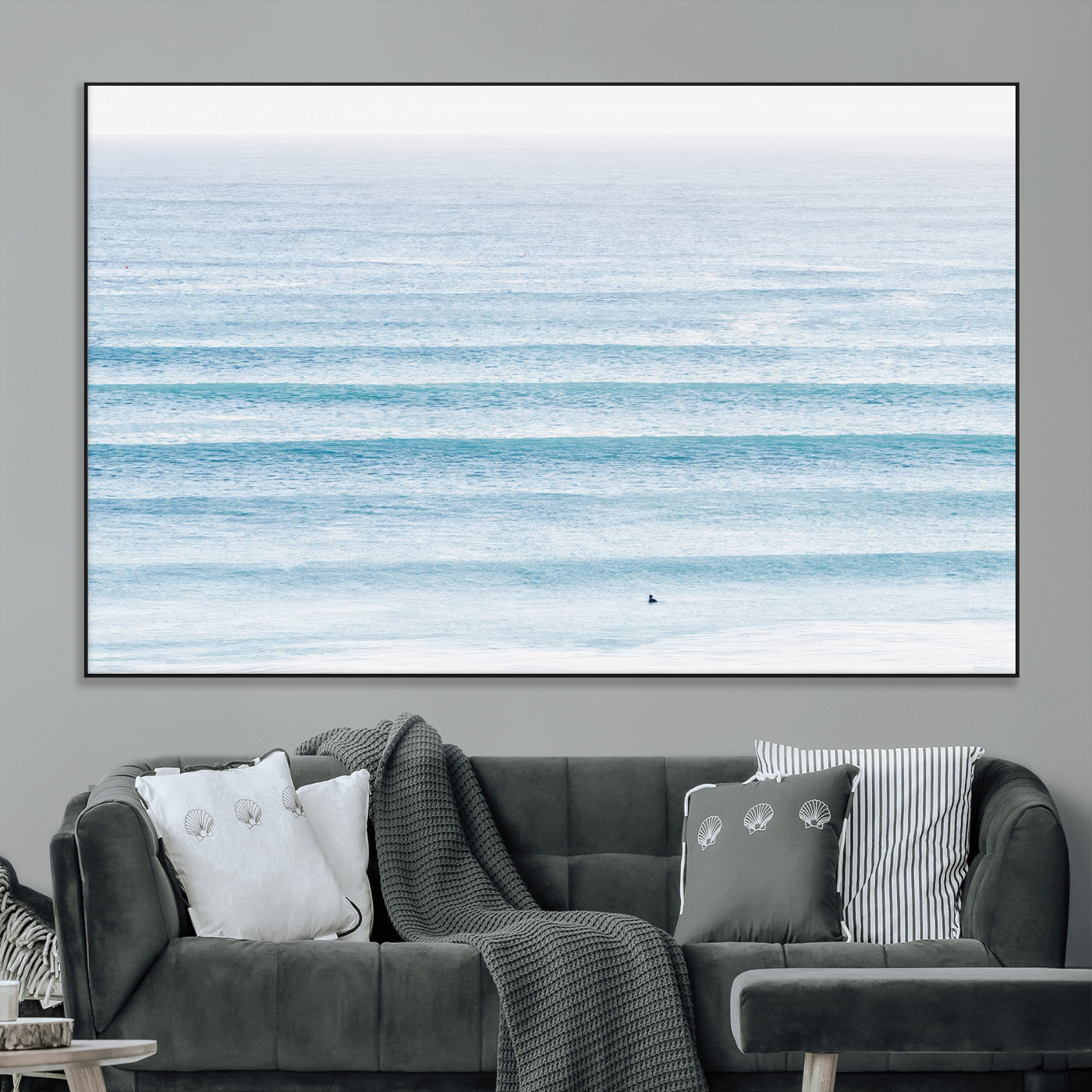Minimalist ocean view with soft blue waves and a lone surfer, creating a serene and airy coastal aesthetic, perfect for tranquil home decor.