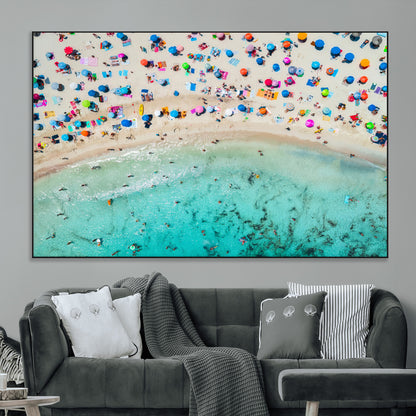 Aerial view of a vibrant beach filled with colorful umbrellas and people enjoying the turquoise ocean, capturing a lively summer vacation scene.