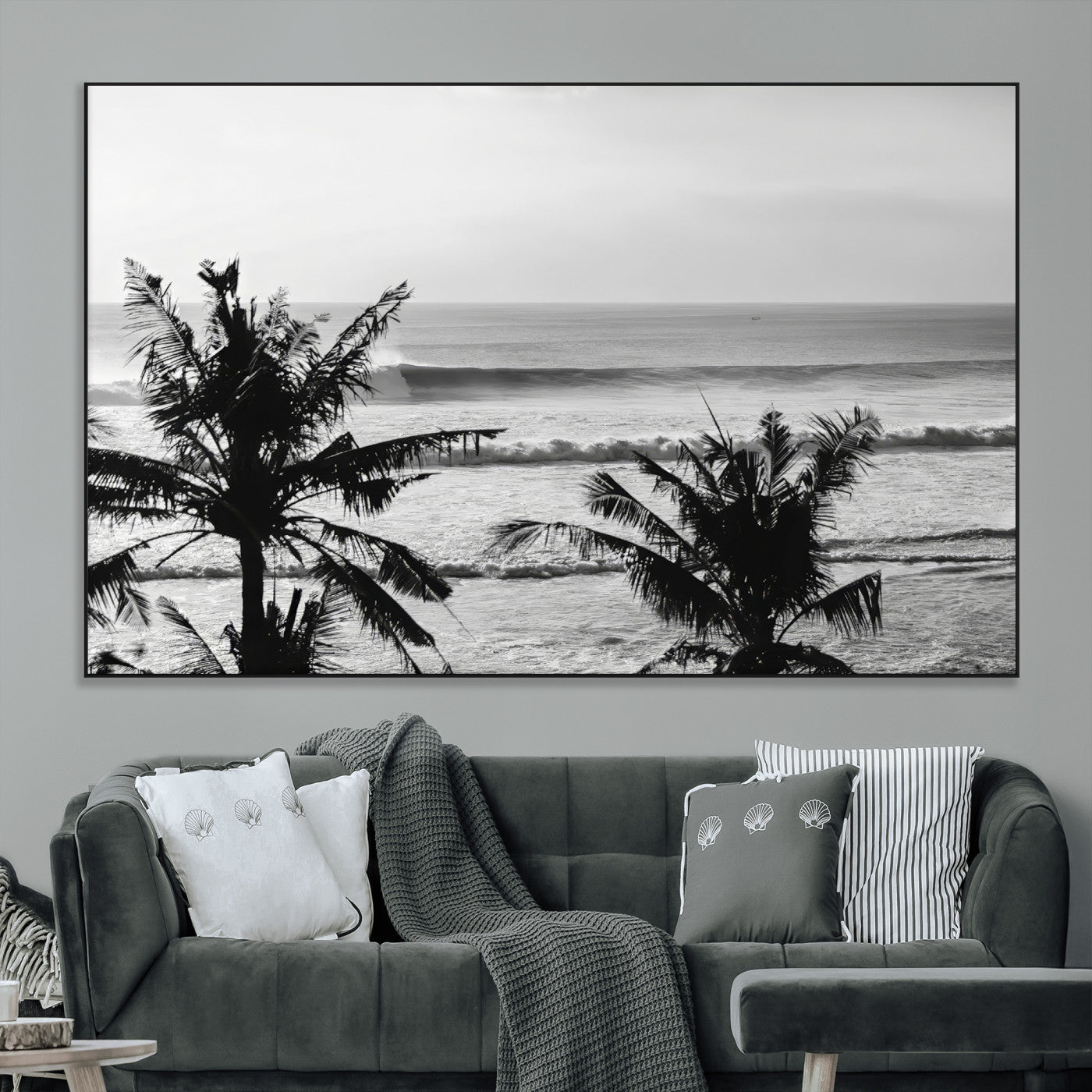Black and white view of ocean waves crashing on a tropical coastline, framed by silhouetted palm trees under a vast, open sky.