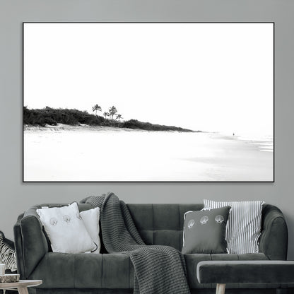 A black and white minimalist coastal scene with a vast open beach, distant palm trees, and a lone figure walking along the shoreline, evoking serenity and solitude.