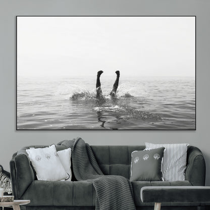 A black and white minimalist water scene capturing a playful splash as a swimmer dives upside down, creating a carefree and artistic aquatic aesthetic.