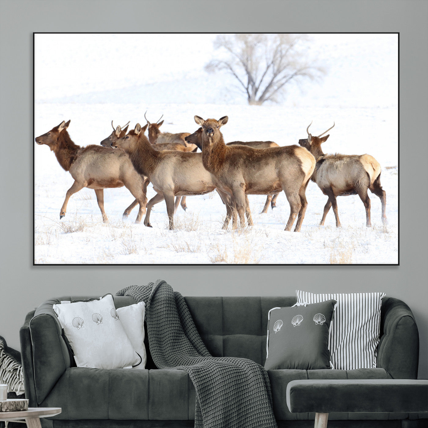 A group of elk standing on snowy terrain with a tree in the background, perfect for rustic or lodge-style winter wall decor.
