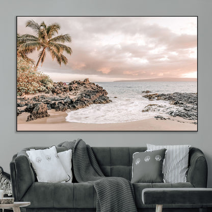 A peaceful beach scene with a palm tree and rocks, soft waves washing onto the shore under a soft pastel sky at sunset.