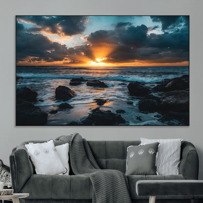 An awe-inspiring sunset over the ocean with rays of light piercing through dramatic clouds, creating a beautiful seascape with rocks in the foreground.
