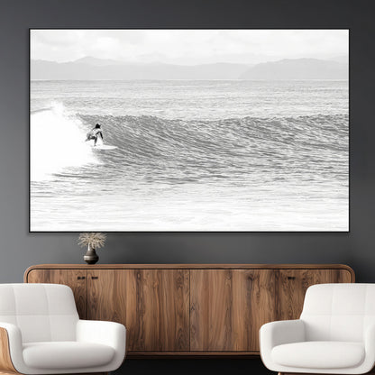 Monochrome photo of a surfer riding a wave with distant mountains, ideal for coastal motion or black and white surf-themed wall decor.