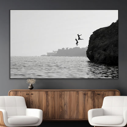 Black and white canvas of two figures cliff jumping into the sea, captured with moody tones, ideal for modern coastal or adventure-themed home decor.   2/2