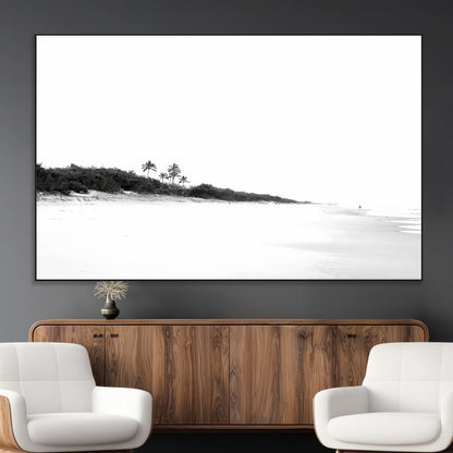 A black and white minimalist coastal scene with a vast open beach, distant palm trees, and a lone figure walking along the shoreline, evoking serenity and solitude.