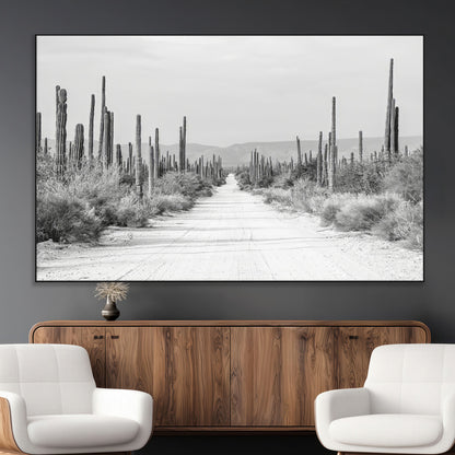 A black and white desert road stretching through a cactus-filled landscape, creating a rugged and timeless southwestern aesthetic with a sense of adventure.