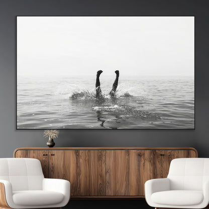 A black and white minimalist water scene capturing a playful splash as a swimmer dives upside down, creating a carefree and artistic aquatic aesthetic.