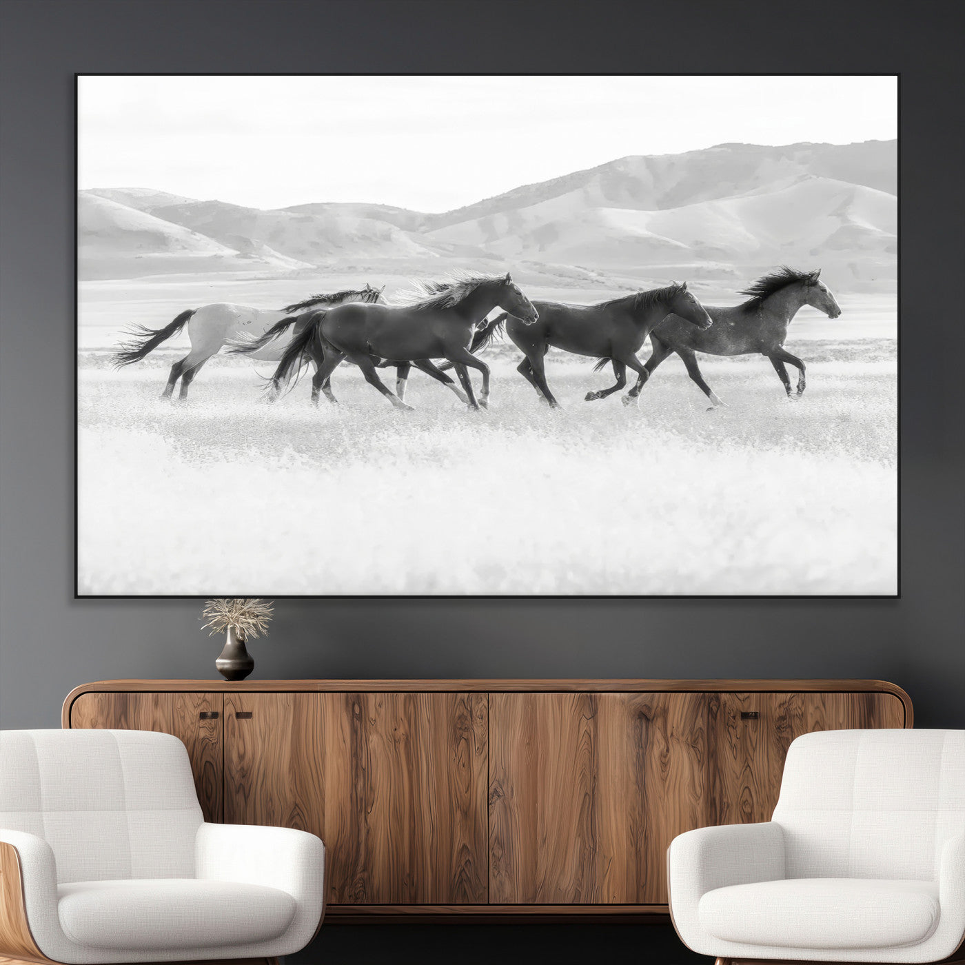 A black and white image of wild horses running freely across an open grassland, capturing the power and beauty of untamed nature in a rustic western setting.