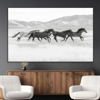 A black and white image of wild horses running freely across an open grassland, capturing the power and beauty of untamed nature in a rustic western setting.