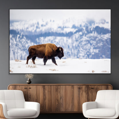 A lone bison walks across snowy ground with blue-toned mountain range behind, ideal for rustic or western farmhouse interiors.