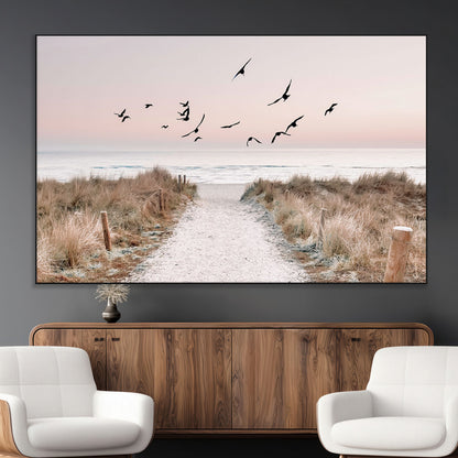 A peaceful coastal pathway leading to the ocean, with birds flying across a soft pastel sky, creating a calm and scenic beach atmosphere.