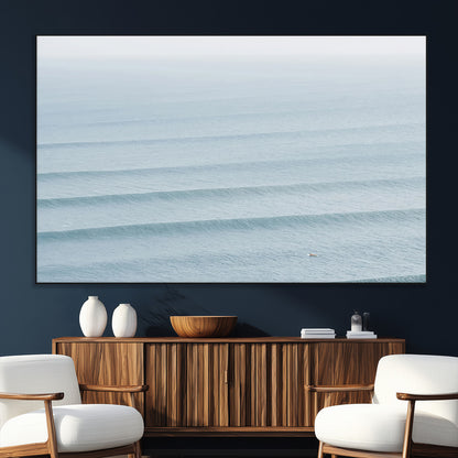 Framed canvas of repeating ocean waves with a distant solo surfer, ideal for minimalist ocean or calm coastal wall decor.