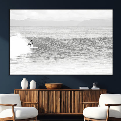 Monochrome photo of a surfer riding a wave with distant mountains, ideal for coastal motion or black and white surf-themed wall decor.