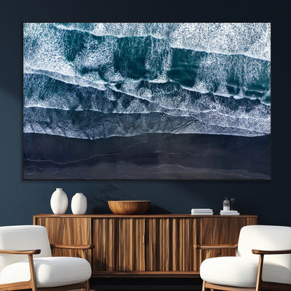 Canvas of aerial ocean waves crashing onto a black sand beach in moody tones, ideal for modern coastal or minimalist home decor.