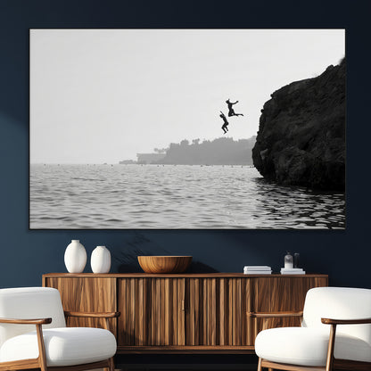 Black and white canvas of two figures cliff jumping into the sea, captured with moody tones, ideal for modern coastal or adventure-themed home decor.   2/2