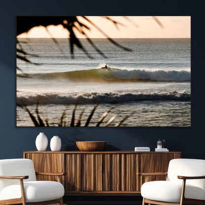 Photo of a surfer riding a golden hour wave at sunset, with tropical tones and dreamy light, perfect for tropical boho or coastal home decor.