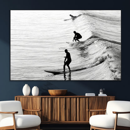 Black and white photo of surfers riding waves in a moody, high-contrast scene, ideal for modern coastal or surf-inspired home decor.