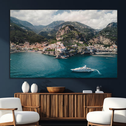 Aerial view of Amalfi Coast, Italy, with colorful hillside houses, lush green mountains, and a luxury yacht sailing in turquoise waters.