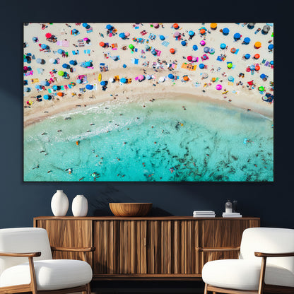 Aerial view of a vibrant beach filled with colorful umbrellas and people enjoying the turquoise ocean, capturing a lively summer vacation scene.