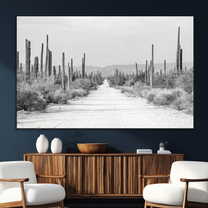 A black and white desert road stretching through a cactus-filled landscape, creating a rugged and timeless southwestern aesthetic with a sense of adventure.