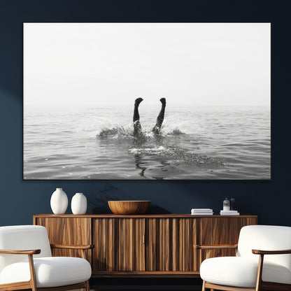 A black and white minimalist water scene capturing a playful splash as a swimmer dives upside down, creating a carefree and artistic aquatic aesthetic.