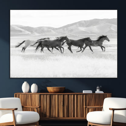 A black and white image of wild horses running freely across an open grassland, capturing the power and beauty of untamed nature in a rustic western setting.