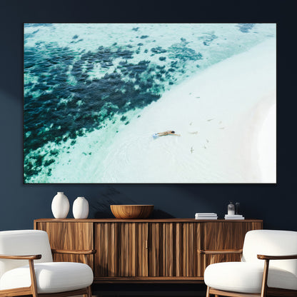 Canvas featuring an aerial view of a swimmer in shallow turquoise waters with coral patterns, ideal for tropical coastal home decor.