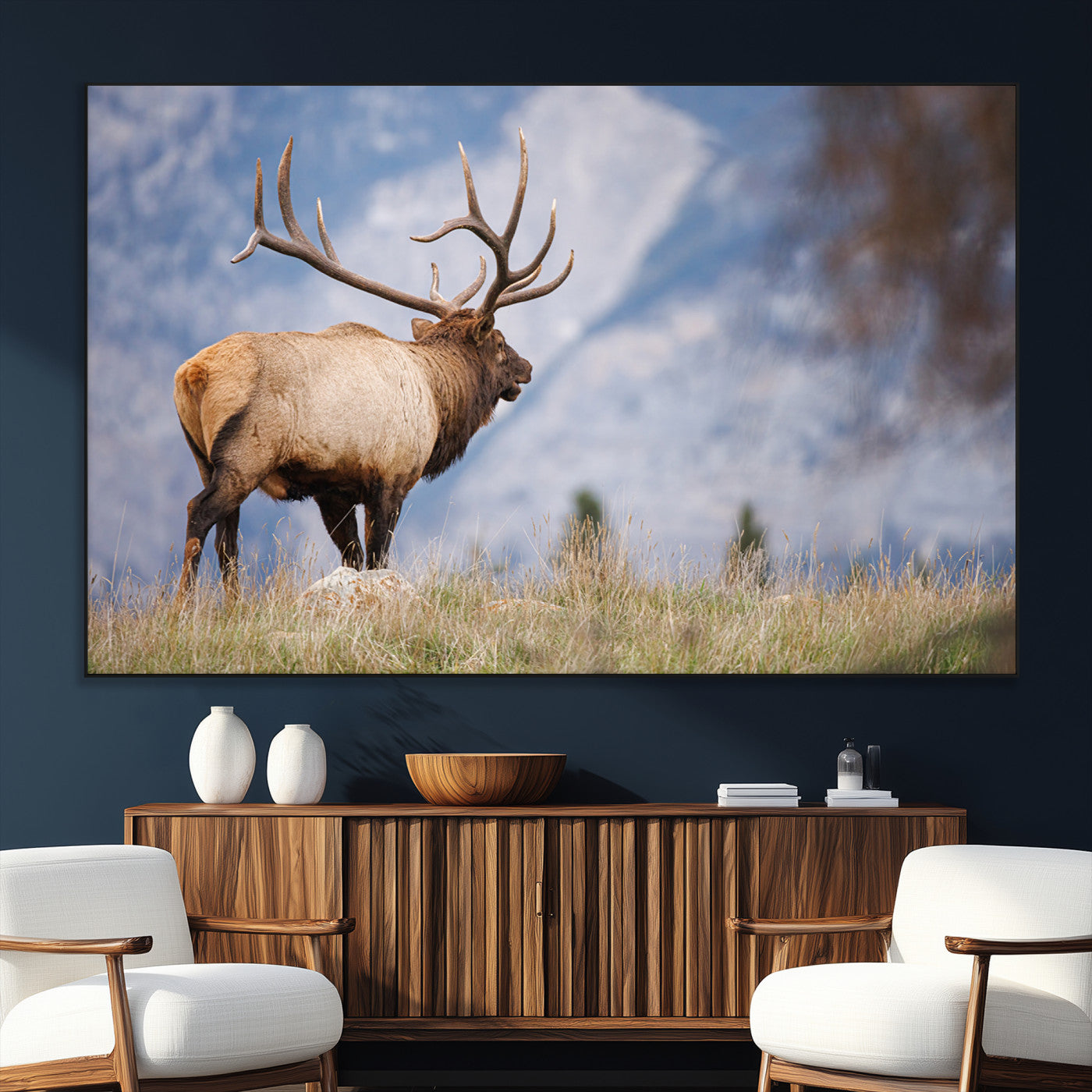 Elk with antlers standing on grass with mountain background, ideal for rustic, cabin, or lodge-inspired wall decor.