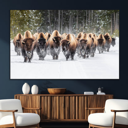 A herd of American bisons walking through a snowy forest path, perfect for rustic cabin or Western-themed wall decor.