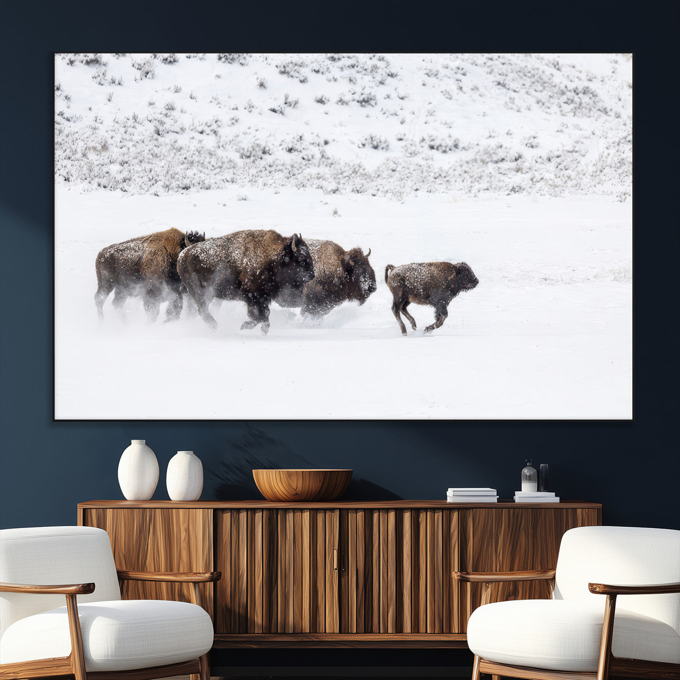 Bison herd running through a snowy open field with mountain backdrop, perfect for rustic or western-themed wall decoration.