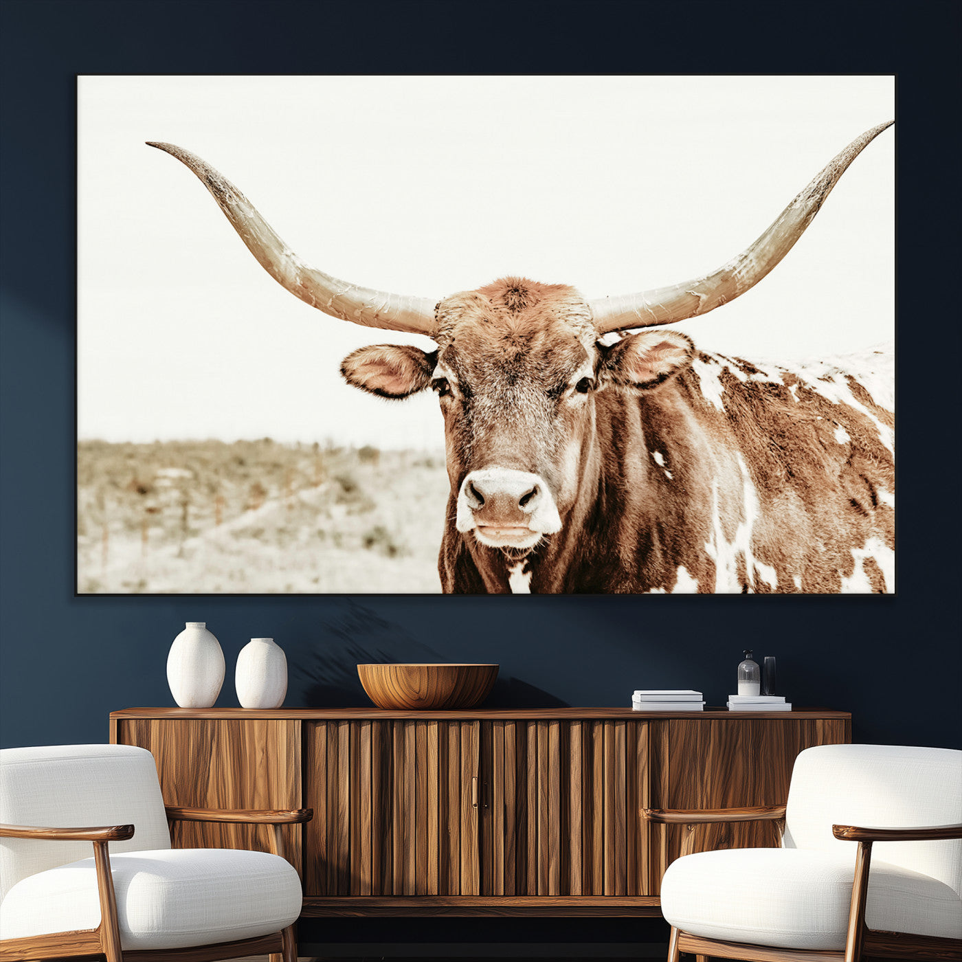A Texas longhorn bull with wide horns, standing in a dry field under soft light, ideal for rustic farmhouse or western-themed interiors.