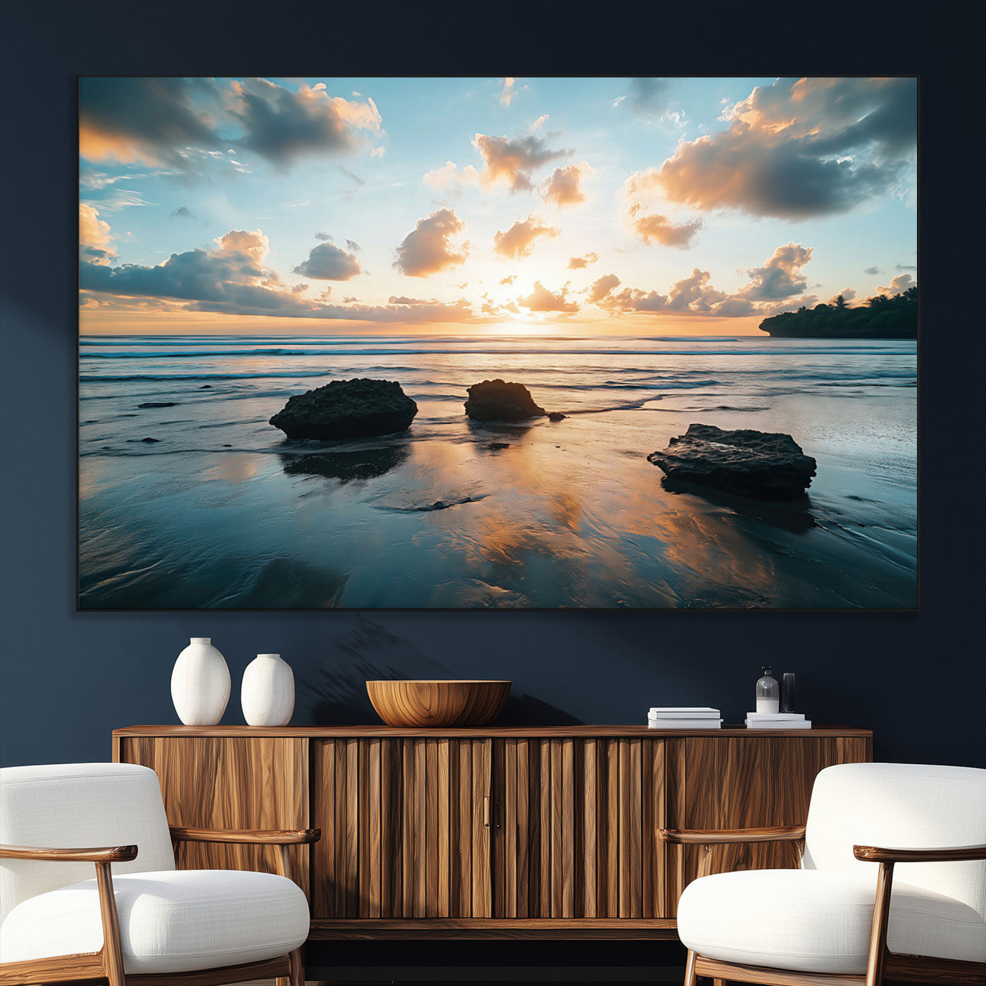 A serene beach at sunset with vibrant clouds, calm water, and rocks in the foreground reflecting the warm colors of the setting sun.