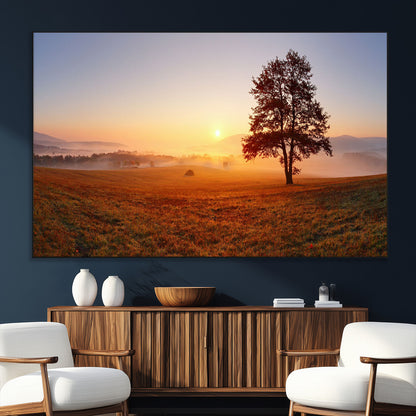 A tranquil landscape at sunrise with a mist-covered field and a lone tree, creating a peaceful and natural atmosphere.
