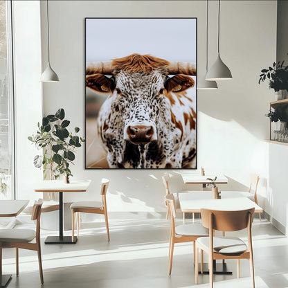 Close-up of a speckled Texas longhorn with wide horns and a bold gaze, perfect for rustic or country-style decor in warm tones.