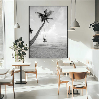 Monochrome photo of a woman swinging from a palm tree on a serene beach, ideal for minimalist or tropical coastal decor.