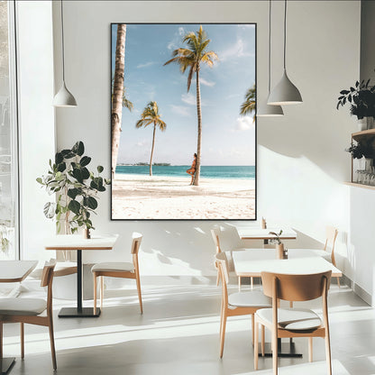 Person leaning on a palm tree at a tropical beach with white sand and turquoise water, perfect for coastal or beach-themed home decor.