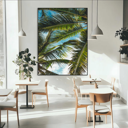 Looking up at lush green palm leaves against a bright blue sky, creating a tropical and relaxing coastal aesthetic.