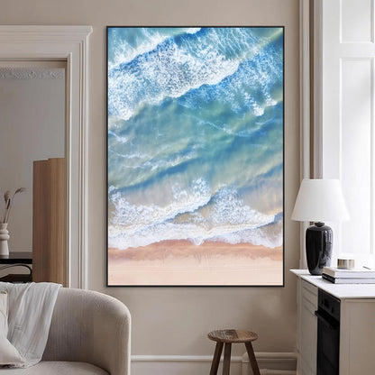 Aerial photo of soft blue waves meeting sandy shore, perfect for modern coastal or beach-themed decor with a light and tranquil aesthetic.