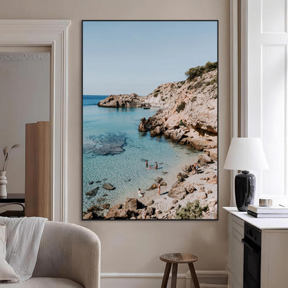 A vibrant coastal photo of a rocky Mediterranean cove with turquoise waters and beachgoers, ideal for boho coastal or summer-inspired interiors.