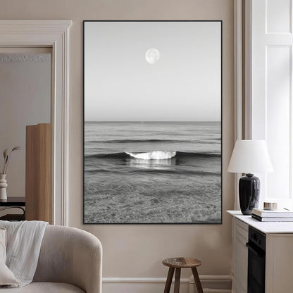 Black and white wall art of a calm ocean wave beneath a full moon, ideal for minimalist or monochrome coastal decor.