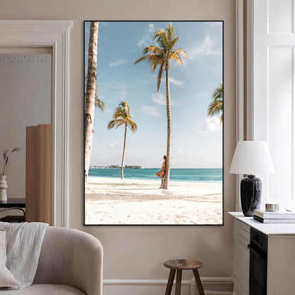 Person leaning on a palm tree at a tropical beach with white sand and turquoise water, perfect for coastal or beach-themed home decor.
