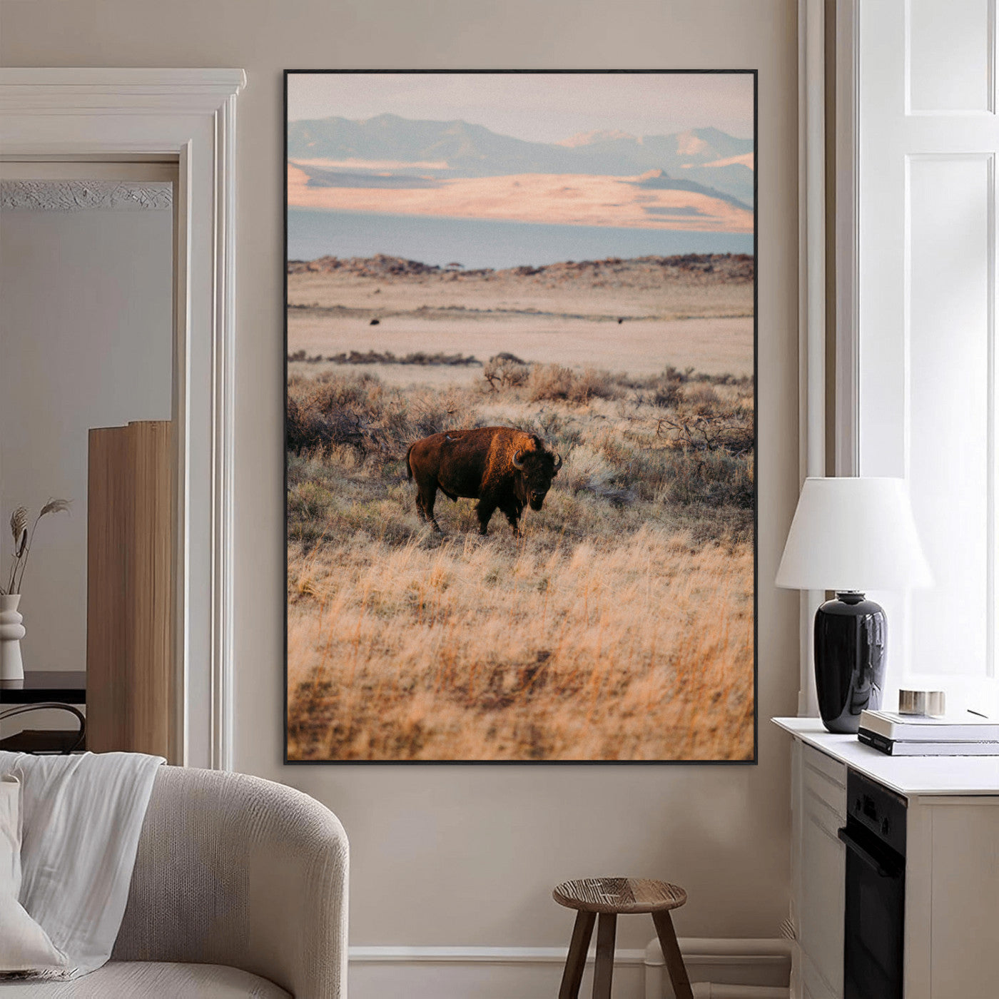 A solitary bison standing in golden prairie grass with distant mountains and soft sunset light, ideal for rustic, lodge, and western decor.