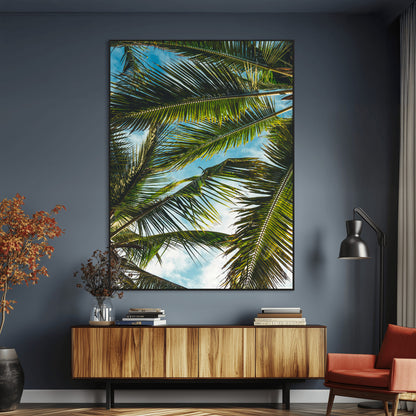 Looking up at lush green palm leaves against a bright blue sky, creating a tropical and relaxing coastal aesthetic.