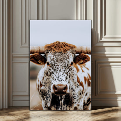 Close-up of a speckled Texas longhorn with wide horns and a bold gaze, perfect for rustic or country-style decor in warm tones.