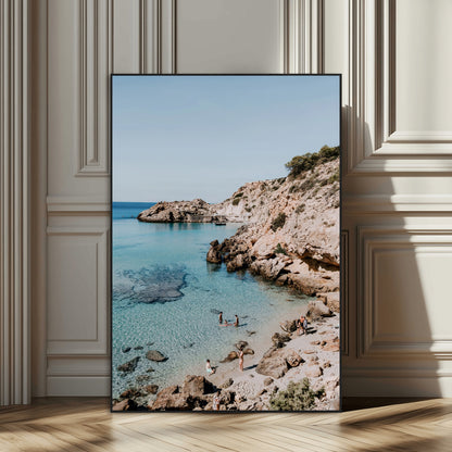 A vibrant coastal photo of a rocky Mediterranean cove with turquoise waters and beachgoers, ideal for boho coastal or summer-inspired interiors.