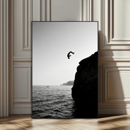 Silhouette of a person mid-air during a cliff jump over the ocean, captured in black and white for minimalist adventure decor.