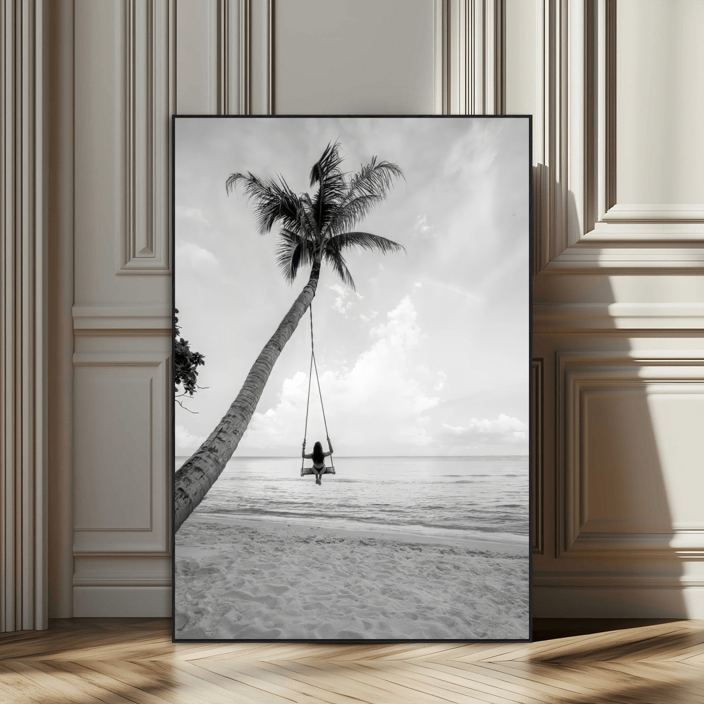Monochrome photo of a woman swinging from a palm tree on a serene beach, ideal for minimalist or tropical coastal decor.
