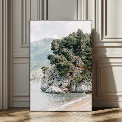 Framed photo of a rocky coastal cliff with dense greenery and calm shoreline, ideal for rustic coastal or earthy-toned home decor.